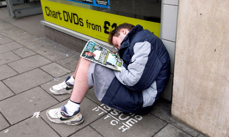 A Big Issue seller asleep on his pitch outside a HMV record shop in Western Road Brighton