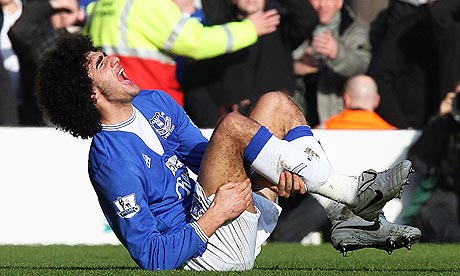 Marouane Fellaini lies in pain after being tackled by Liverpool defender Sotirios Kyrgiakos 