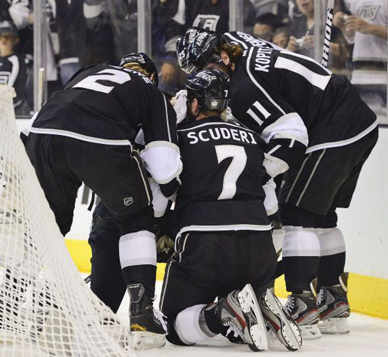 Los Angeles Kings defenceman Rob Scuderi is helped up by teammates