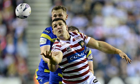 Wigan's Ben Flower loses control of the ball as he is tackled by Ben Currie of Warrington Wolves