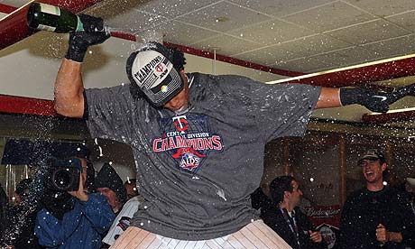 Carlos Gomez of the Minnesota Twins celebrates on a table in the locker room after they beat Detroit