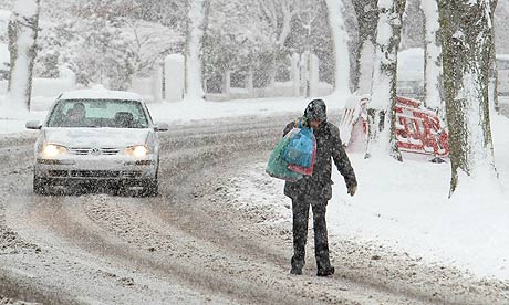 A man walks along a snow covered road ne