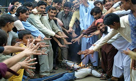 Pakistan cricket fans gesture beside a burning effigy of captain Salman Butt during a protest