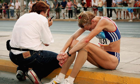 Paula Radcliffe sits on the curb after pulling out of the women's marathon 