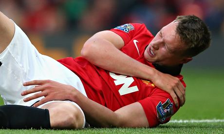 Manchester United's Phil Jones grimaces as he clutches his injured shoulder.