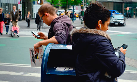 Two people leaning on mail box while using iPhones near Columbus Circle, New York City