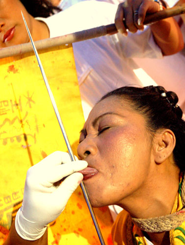 Here, a female medium gets her tongue pierced at the Kathu shrine