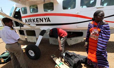 Masai  woman checks in in the shadow of a small plane at WIlson airport, Nairobi