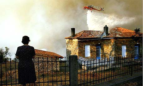 A firefighting helicopter drops water during a fire in the village of Thisoa, in the Peloponnese