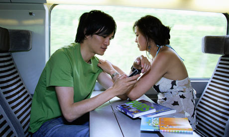 Couple tavelling on a train with guide books and phones