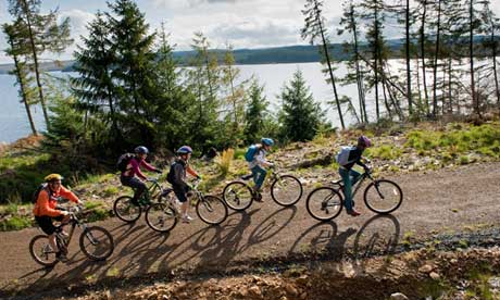 Family cycling along the Lakeside Way, Kielder Water & Forest Park, Northumberland, England.