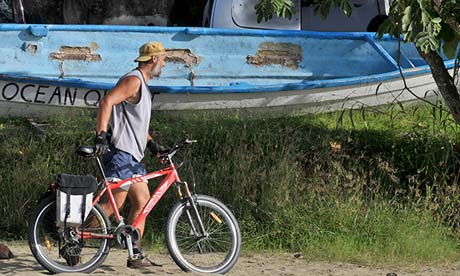 Man with bike on beach in Tobago.