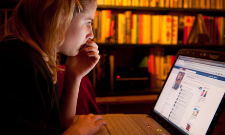 A teenage girl reading her Facebook page on a laptop computer at home, UK