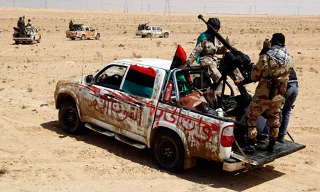 Rebel fighters ride in vehicles as they drive in the desert along the Benghazi-Ajdabiyah Road