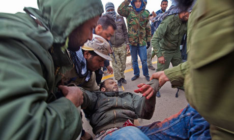 A wounded rebel fighter is transferred to an ambulance near Ajdabiya