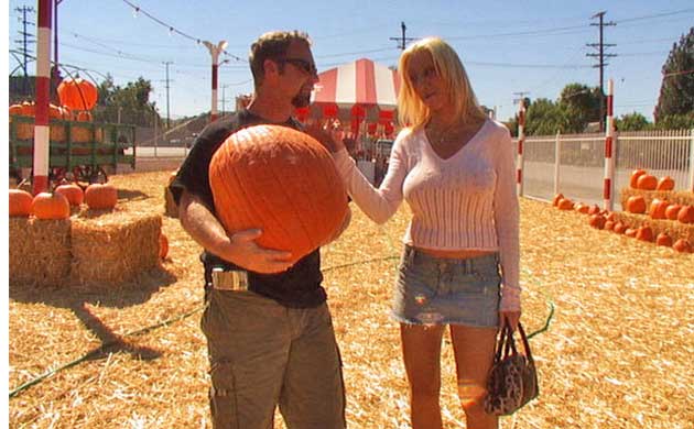 A woman touches her friend's giant pumpkin