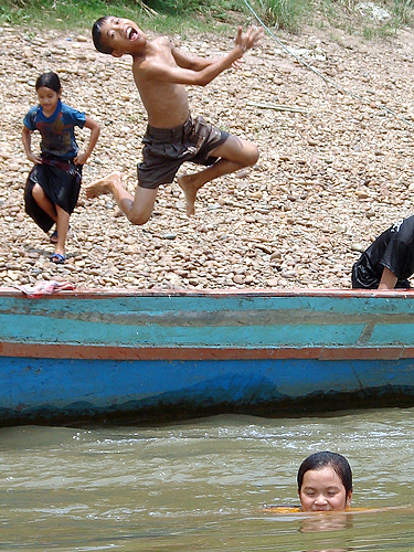 Children jumping from a longtail boat on the Mekong River