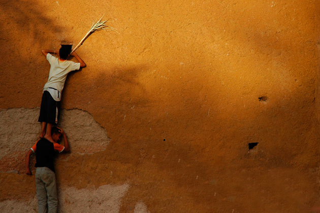 Boys looking through a hole in a wall, Morocco