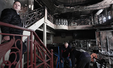 Workers clear a burned out cafe in central Athens on Monday February 13, 2012. 
