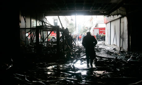 A man walks inside the burnt atrium of a mall after violence in Greece, on 13 February 2012. 