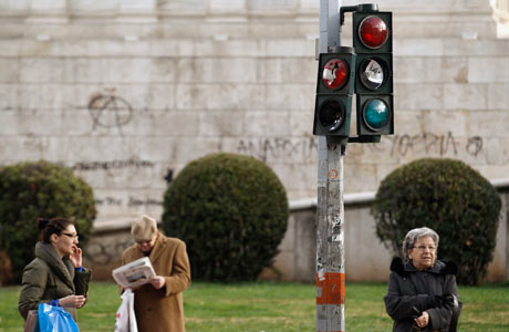 Commuters are seen around a destroyed traffic light after violent protest in Athens, 14 Feb 2012.