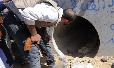 An NTC fighter looks through a large concrete pipe where ousted Gaddafi was allegedly captured