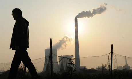A man walks past as smoke billows from chimneys at a power station in Hefei, China