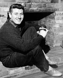 Jack Clement sitting by a fireplace