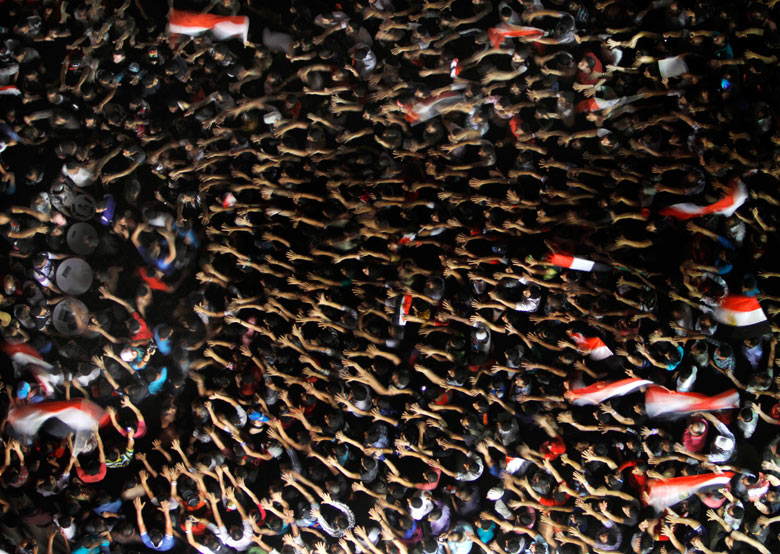 Egyptian protesters wave their hands and hold national flags during a demonstration against president Mohamed Morsi in Tahrir Square Amr Nabil/AP