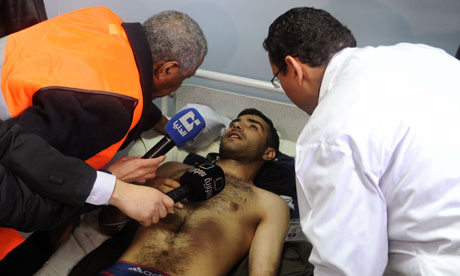 An Arab league observer listens to a Syrian injured man 