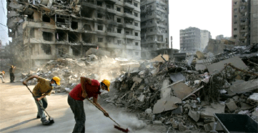 Lebanese Hizbullah supporters sweep the street in a destroyed residential area in southern Beirut