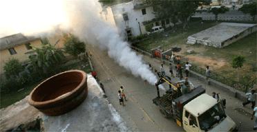Children play in the fumes of a municipality fumigant sprayer as it goes through a residential area in New Delhi, India