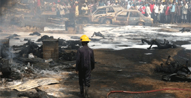 A rescue worker walks among charred corpses after firefighters extinguished a blaze resulting from an early morning pipeline explosion in Lagos, Nigeria