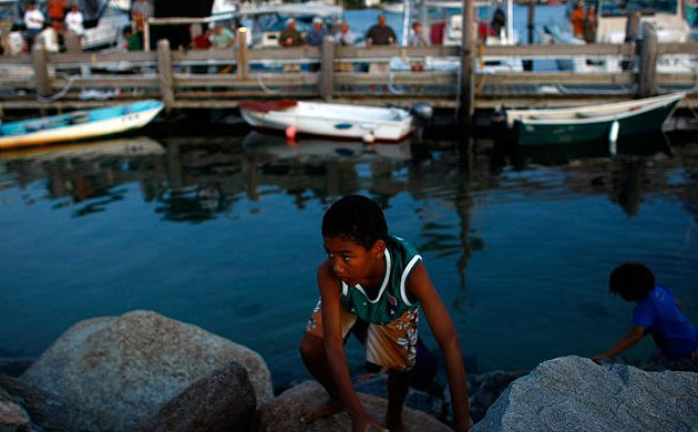 A boy climbs up from the water after trying to catch baitfish in Menemsha, Massachusetts on the island of Martha's Vineyard