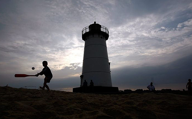 A young boy plays in front of a lighthouse in Edgartown, Massachusetts on Martha's Vineyard 