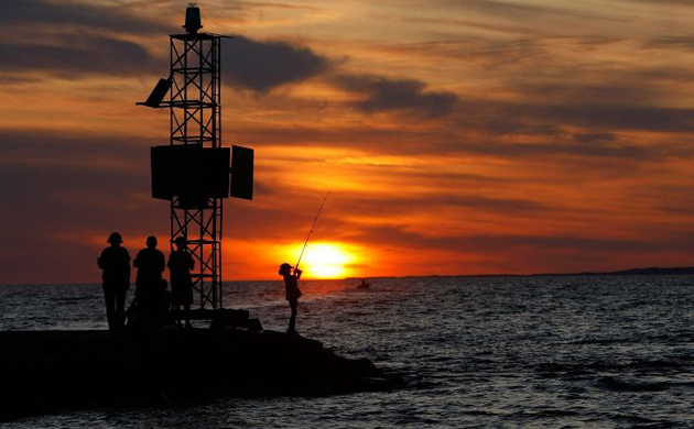A girl fishes as the sun sets in Menemsha, Massachusetts on the island of Martha's Vineyard