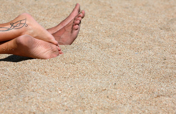 Costa Brava or Bahamas?: Holidaymakers's feet on the Platja de Lloret beach, Costa Brava, Spain.