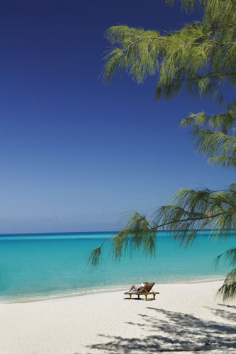 Costa Brava or Bahamas?: A woman relaxes on a sunlounger on a beach, Salt Cay, Turks and Caicos.