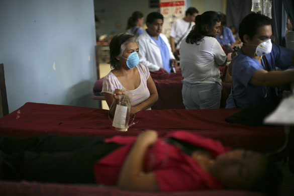 Swine flu pandemic: A woman wearing a face mask waits for a doctor in San Juan de Dios hospital