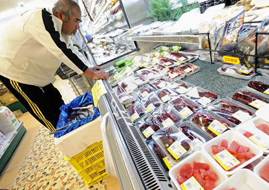 Dolphins in Japan: A man looks at the dolphin meat and other sashimi products at a supermarket
