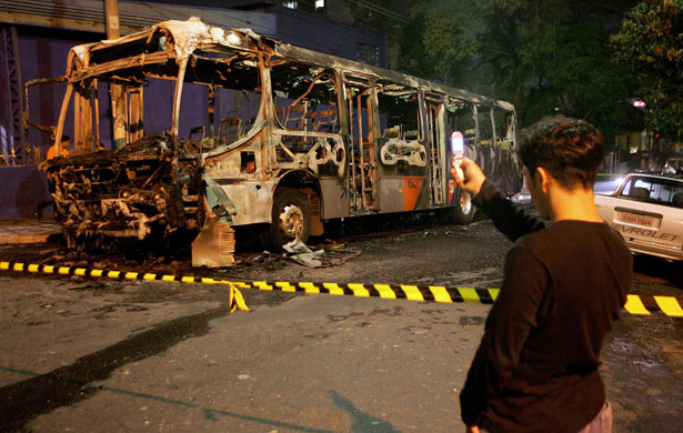 Rise of the camera-phone: A man uses a cell phone to photograph a burnt-out bus in Sao Paulo