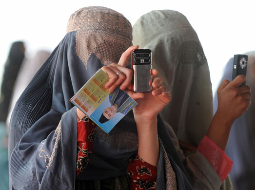 Rise of the camera-phone: Burqa-clad Afghan women at an election gathering wait for President Karzai