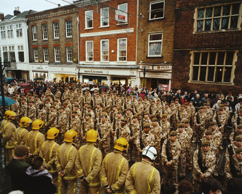 Isolation: A street is packed with rows of expectatnt soliders and firemen