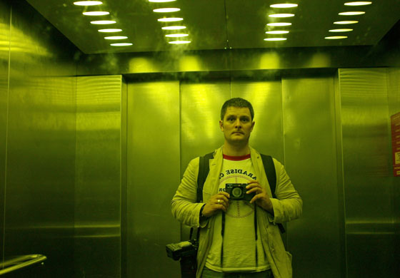 Isolation: A man stands in a lift taking a self portrait in the mirror