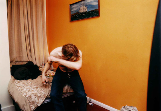 Isolation: A man sits on a hostel bed, hiding his face