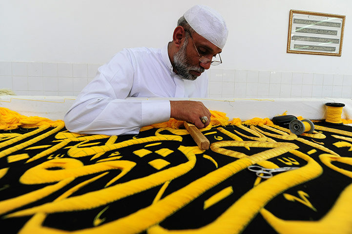 Hajj In Mecca: A Saudi worker sews Islamic calligraphy on a drape in Mecca