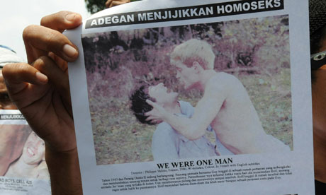 A protester against the Q! film festival in Jakarta holds a placard featuring two gay films
