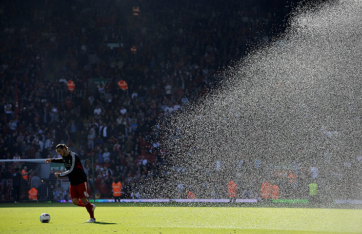 Liverpool v United: Andy Carroll tries to escape a drenching whilst warming up at half-time 