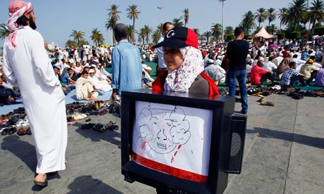 A girl carries a TV with a drawing of Muammar Gaddafi in Martyrs Square, Tripoli, Libya