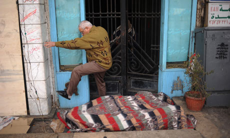 An Egyptian man jumps over an anti-government protester in front of the door of his residence